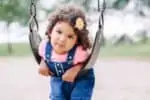 Hispanic girl playing on a swing in the park