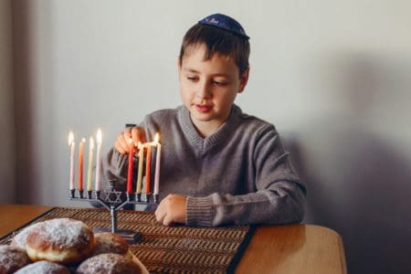 Hebrew boy in lighting candles for Jewish Hanukkah holiday