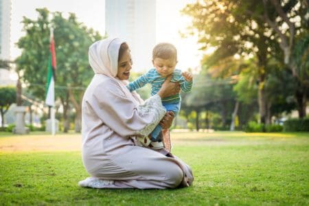 Arabic toddler boy and mother playing together at the park in Dubai