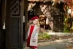 Adorable girl in old-fashioned clothes and red beret on a walk in the fall