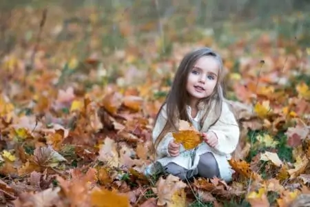 Russian girl sitting on autumn leaves