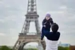 Father throwing his little kid in the air near the Eiffel Tower