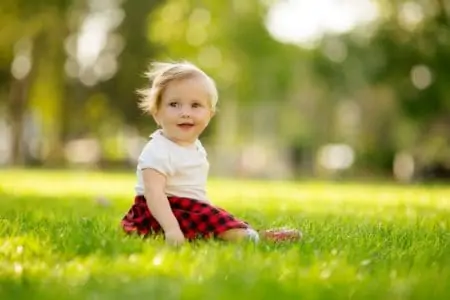 Cute Gaelic baby girl sitting on grass