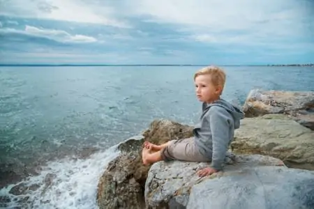 Australian boy kid sitting on a stone looking far away