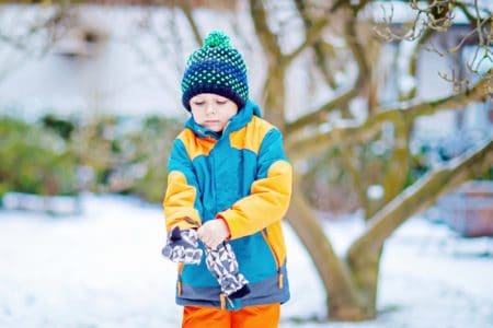 Finnish boy child wearing his gloves in the snow