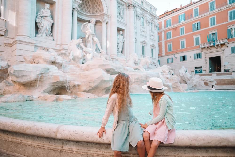 Roman sisters sitting in front of Fountain of Trevi in Rome