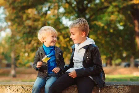 Two happy little kids having fun with each other in autumn park