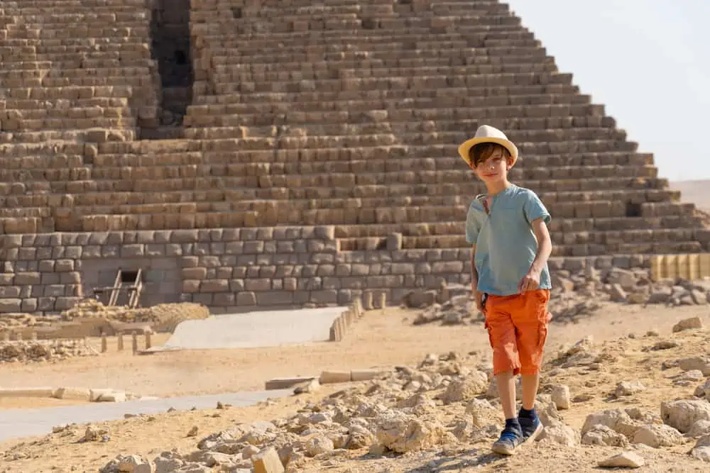 Egyptian young boy walking in front of a pyramid