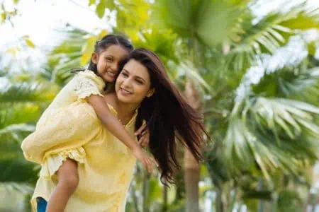 Indian mother giving piggyback ride to her daughter