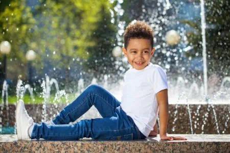 Brazilian young boy sitting near fountain