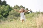 European little girl running in country field in summer