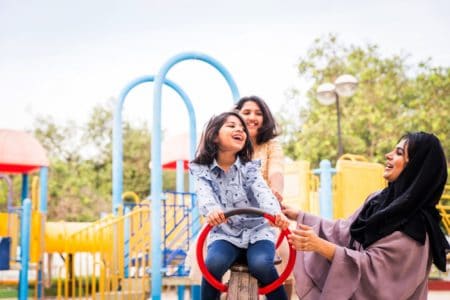 Persian sisters playing in the park with mother
