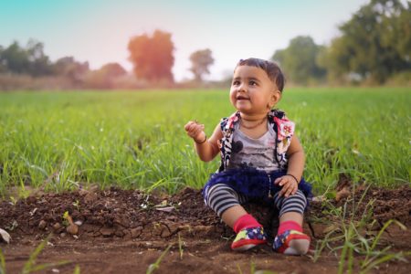 Hindi little girl sitting on soil in the farm