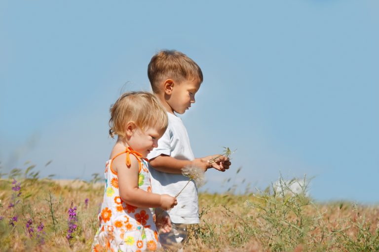 Maori kids holding dandelions playing in green meadow