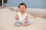 Thai adorable toddler boy sitting on sand near beach