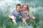 Two adorable kids sitting on flower field
