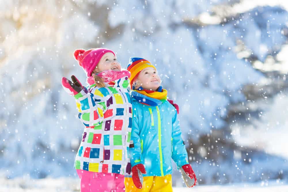 Kids wearing winter outfit playing in snow outdoors