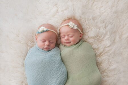 Twin baby girls sleeping on white faux rug