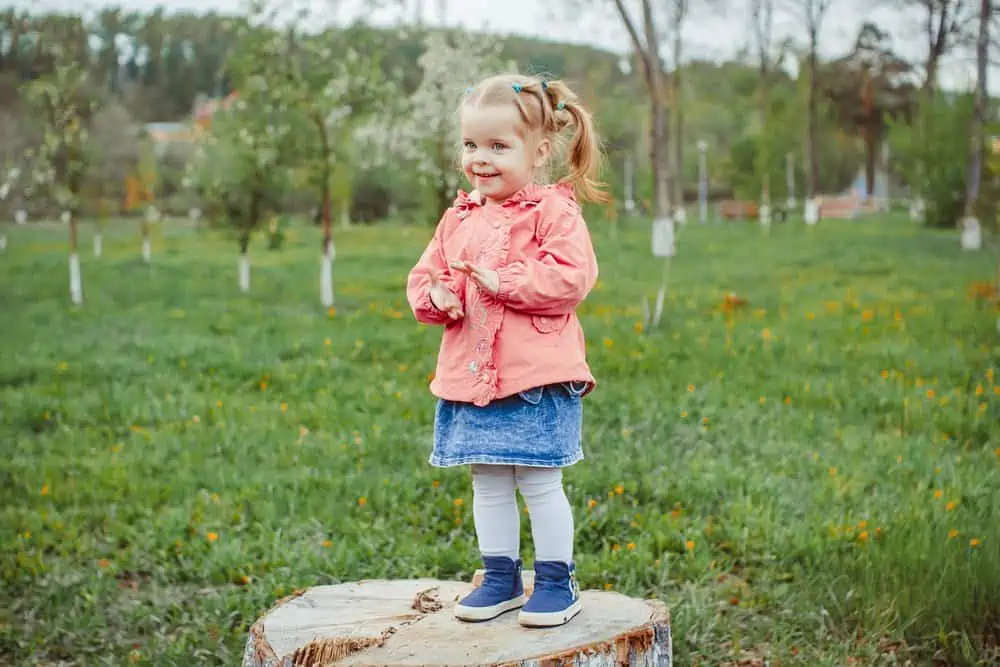 Short cute girl standing on wood in the park