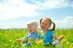 Cheerful girl and boy having fun on green meadow