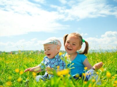 Cheerful girl and boy having fun on green meadow