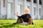Cute little boy dressed as medieval knight sitting on the grass outdoors