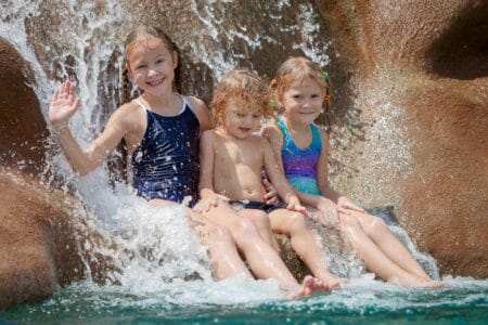 Three happy kids sitting near the pool in the waterpark
