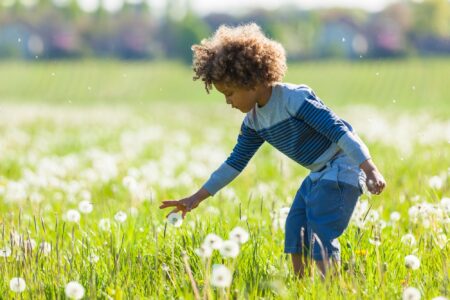 Cute african american little boy playing in flower field