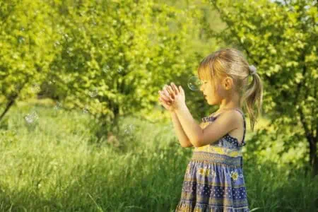 Adorable little girl praying in the sunny park