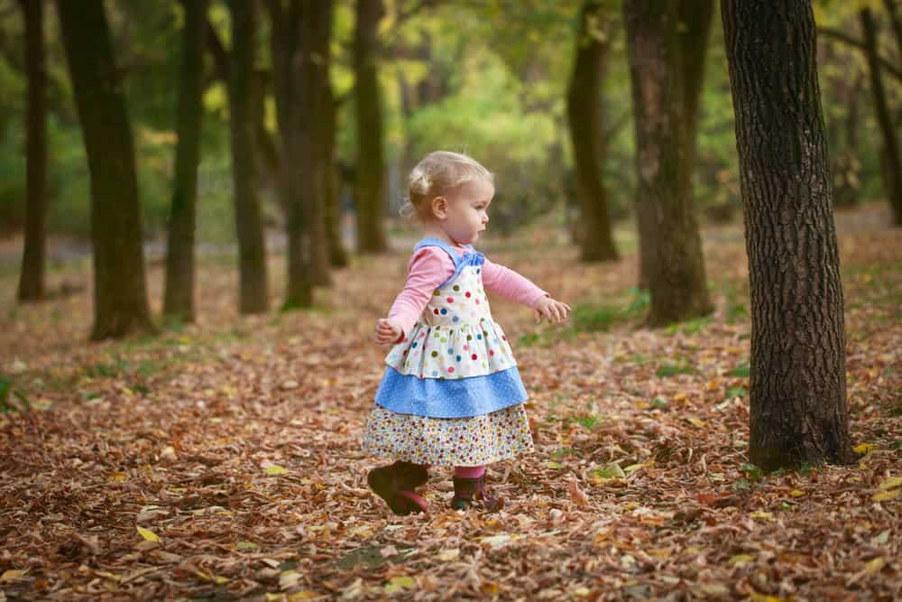 Victorian little adorable girl walking in autumn park