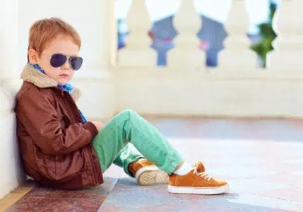 Badass stylish boy in leather jacket and sunglasses sitting on the ground