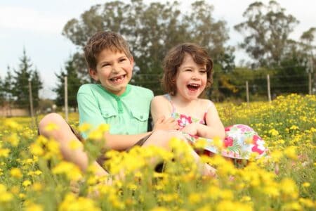 Scottish kids happily sitting in field of beautiful flowers