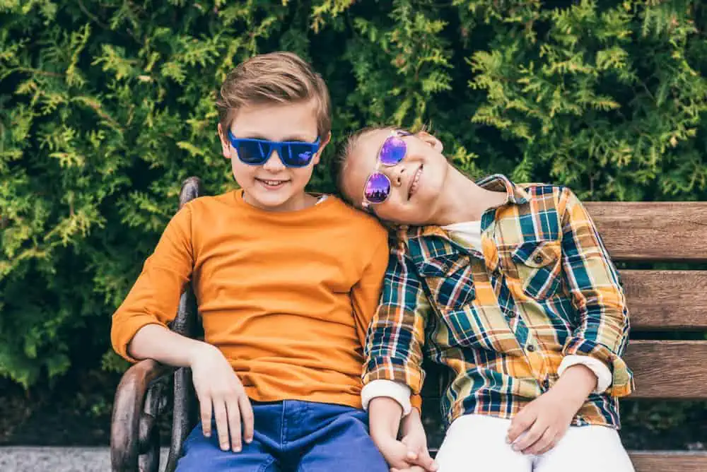 Cool kids wearing stylish sunglasses sitting on beach at the park