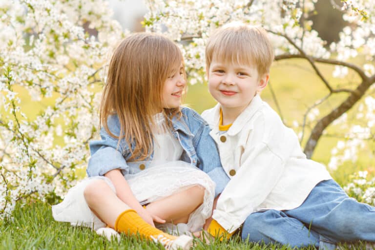 Beautiful children sitting on grass in spring park