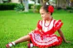 Gypsy girl wearing traditional costume sitting on the grass at the park
