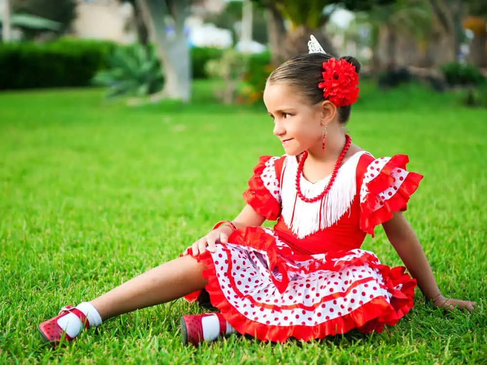 Gypsy girl wearing traditional costume sitting on the grass at the park