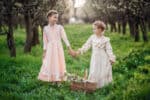 Two adorable girls in medieval dress holding hands in the park