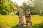 Native american toddler boys playing bow outdoors