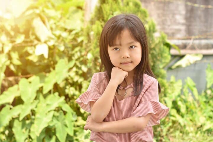 Vietnamese little girl playing in the park on summer day