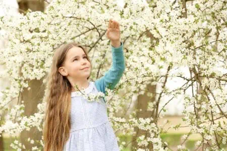 Adorable little girl reaching the flowers in spring park