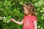 Cute toddler girl touching flowers in the garden