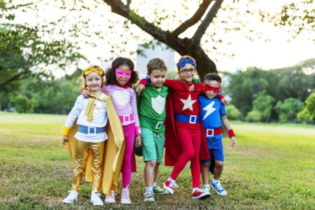 Cheerful kids wearing superhero costumes in the park