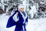 Russian boy in blue suit standing in the snow outdoors