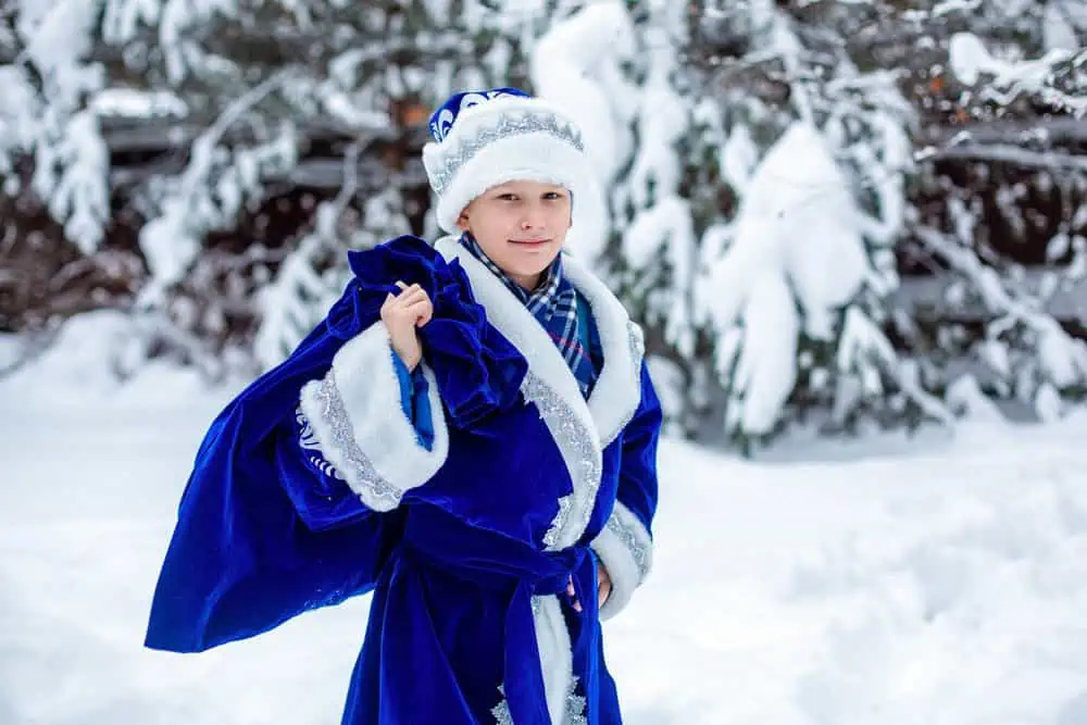 Russian boy in blue suit standing in the snow outdoors