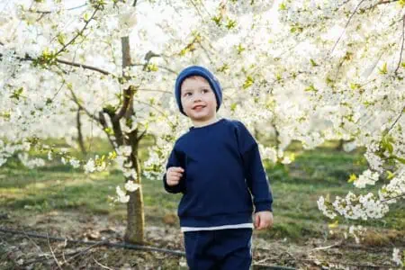 Cheerful young boy standing in blooming garden