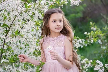 Beautiful little girl in pink dress in spring garden