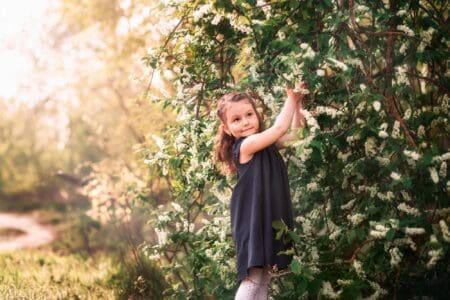 Adorable little girl in dress picking flowers in the garden