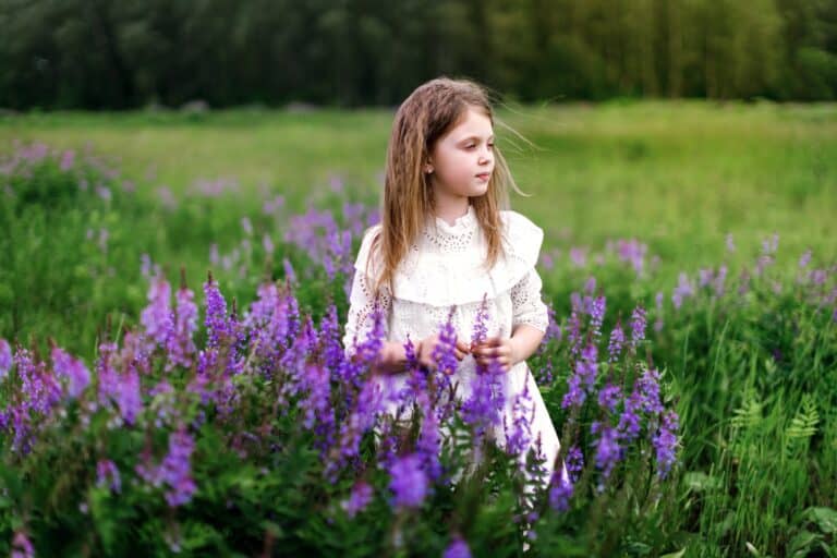 Beautiful girl in white dress standing in the midst of lavender field