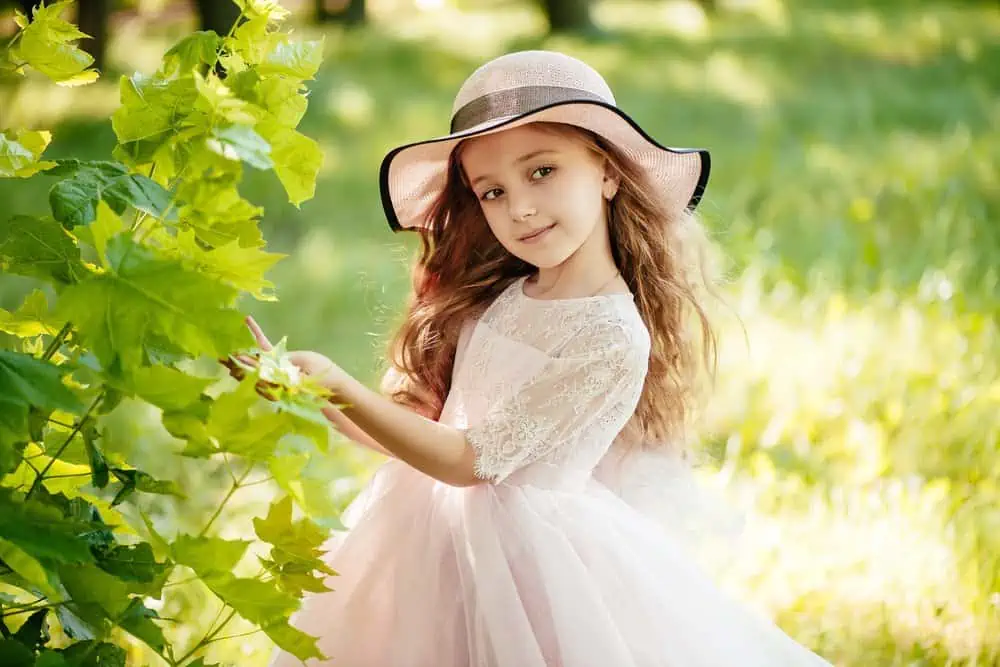 Victorian little girl in dress and stylish hat in the garden