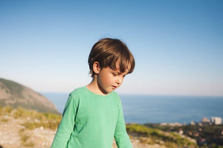 Handsome young boy at the top of the mountain at sunset